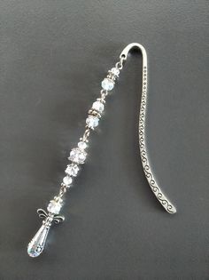 a metal hook with crystal beads and a chain attached to it on a black surface