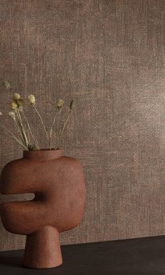 a vase with flowers in it sitting on a table next to a wallpapered background