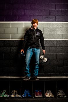 a young man standing in front of a wall with shoes