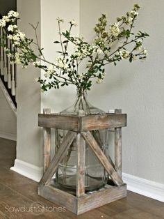 a vase filled with white flowers sitting on top of a wooden table next to a stair case