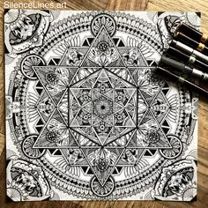 an intricate coloring book with black and white designs on the cover, surrounded by markers