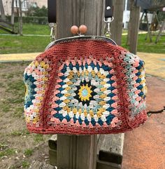 a crocheted purse hanging from a wooden post