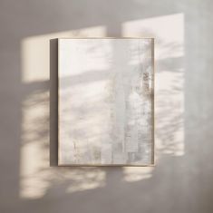 an abstract painting hangs on the wall in front of a window with sunlight streaming through it