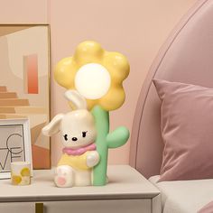 a lamp that is sitting on top of a table next to a bed with pink pillows