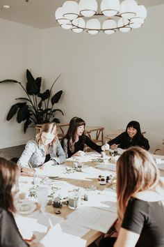 four women sitting around a table with papers on it