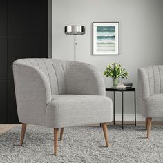 two gray chairs sitting next to each other on top of a carpeted room floor