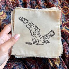 a person holding up a piece of cloth with an image of a bird on it