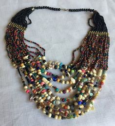 "Multi-color bead statement necklace with a tribal African flair. Lots of different shapes and colors, including a few tiny shells. About 18\" long, hangs about 4\" deep on your chest. Also, please take a look at my storefront at: https://www.etsy.com/shop/FabFinds42?ref=seller-platform-mcnav I have a wide selection of one-of-a-kind items, from clothing and toys to home decor and gift items, and I add new things almost every day." Multicolor Wooden Beads For Festival, Bohemian Beaded Necklaces For Beach With Polished Beads, Multi-strand Wooden Beads For Jewelry Making, Bohemian Multicolor Heishi Beads, Wooden Multi-strand Beads For Jewelry Making, Artisan Multicolor Multi-strand Beaded Necklaces, Artisan Multicolor Beaded Chain Necklace, Artisan Multicolor Beaded Necklace For Beach, Artisan Multicolor Multi-strand Beads