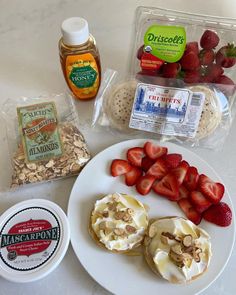 some strawberries, yogurt and granola on a white plate with other ingredients