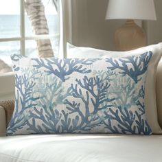 a blue and white pillow sitting on top of a couch next to a window in a living room