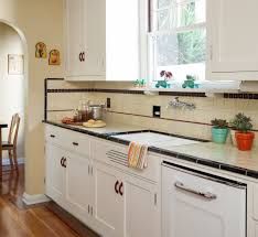 a kitchen with white cabinets and black counter tops next to a dining room table in front of a window