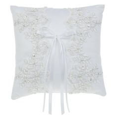 a white pillow with embroidered flowers on the front and ribbon at the back, tied in a bow