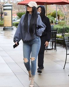 a woman walking down the street in ripped jeans