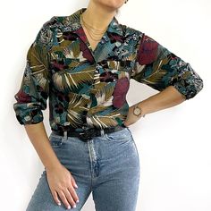 Beautiful, dark tropical print ladies shirt with long sleeves, an open v-neck collar and two chest pockets. It is made from soft, light viscose and has a straight, loose shape. Made in Romania by LNO Sportswear Associates Inc. 100% viscose. Medium size, measurements when laid flat are: Pit to pit: 49cm Waist: 46cm Hemline: 50cm Length: 58cm Sleeve length: 52cm Excellent condition. Black Hawaiian Shirt Outfit, Casual Long Sleeve Tops With Plant Print, Summer Long Sleeve Shirt With Plant Print, Long Sleeve Shirt With Tropical Print For Spring, Long Sleeve Shirt With Plant Print For Summer, Green Tropical Print Top With Camp Collar, Casual Blouse With Plant Print, Tropical V-neck Top With Floral Print, V-neck Floral Print Relaxed Fit Shirt