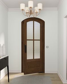 an empty room with a wooden door and chandelier above the entrance to another room