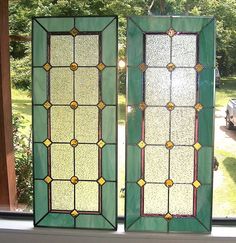 two stained glass windows sitting on top of a window sill next to each other