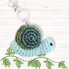 a crocheted keychain with a blue and green snail on it's back