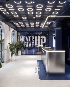 an office lobby with a counter and plant in the center that says never up give up