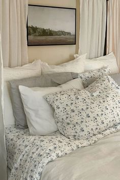 a bed with white sheets and pillows in a bedroom next to a painting on the wall