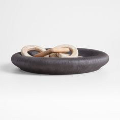 a black and white bowl with two wooden rings in the center on a white background