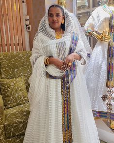 a woman standing in front of a white dress with gold trims on her head