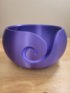 a purple bowl sitting on top of a wooden table next to a heart shaped object