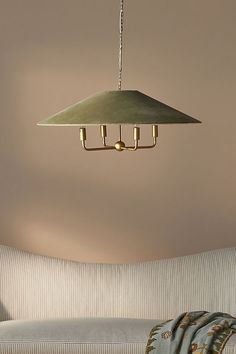 a light fixture hanging from the ceiling in a living room with a couch and throw pillows