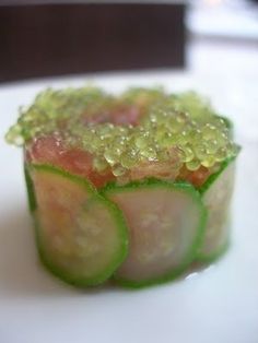 a white plate topped with cucumber slices covered in green sauce and sprinkles