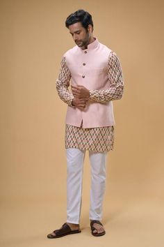 Peach sleeveless bundi crafted in cotton silk. Paired with an ikat print kurta and pant. - Aza Fashions Transitional Sleeveless Cotton Kurta, Fitted Pink Nehru Jacket For Transitional Season, Pink Fitted Nehru Jacket For Transitional Season, Transitional Pink Fitted Nehru Jacket, Transitional Fitted Pink Nehru Jacket, Cotton Sleeveless Nehru Jacket For Festive Occasions, Traditional Pink Cotton Nehru Jacket, Festive Cotton Sleeveless Nehru Jacket, Festive Sleeveless Cotton Nehru Jacket