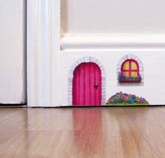 there is a toy house with a pink door and flower pot on the floor next to it