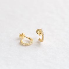 "These tiny open-hoop stud earrings are adorned with brilliant cubic zirconia gemstones. They're the perfect huggie hoop size for layering with other dainty hoops and studs. A dainty, elegant and versatile addition to your everyday lineup. ∙ Sold as a PAIR * D E T A I L S * ∙ Material: .925 Sterling Silver or 18K Gold Plated over .925 Sterling Silver ∙ Stone: White Cubic Zirconia ∙ Dimensions: Outer diameter: 11mm // Inner diameter: 7mm ∙ Hypoallergenic & nickel-free * P A C K A G I N G * ∙ Gift Cubic Zirconia Hoop Cartilage Earrings, Cubic Zirconia Huggie Hoop Earrings With Ear Wire, Pierced Cubic Zirconia Huggie Diamond Earrings, Dainty Cubic Zirconia Small Hoop Huggie Earrings, Small Hoop Cubic Zirconia Huggie Earrings, Cubic Zirconia Huggie Jewelry, Dainty Cubic Zirconia Hoop Earrings With Ear Wire, Small Hoop Cubic Zirconia Cartilage Earrings For Anniversary, Minimalist Small Hoop Cartilage Earrings In Cubic Zirconia