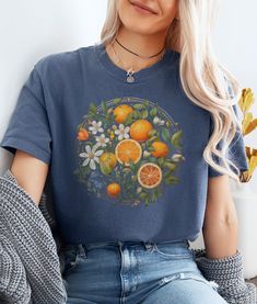 Embrace floral mystique in our citrus blossom tee, where vibrant wildflowers dance alongside zesty citrus blooms under the moon's soft glow. Let the enchantment of nature illuminate this cozy design. ★ Fabric ★ The Comfort Colors 1717 tee is made with medium fabric (6.1 oz/yd² (206.8 g/m consisting of high quality, 100% ring-spun US cotton for long-lasting comfort. Made using 100% US cotton that is ethically grown and harvested. ★ Fit ★ The relaxed fit keeps the wearer comfy in both casual and s Relaxed Fit T-shirt With Fruit Print For Spring, Multicolor Fruit Print Spring Top, Multicolor Fruit Print Tops For Spring, Spring Fruit Print Crew Neck Tops, Blue Floral Print T-shirt For Fall, Yellow T-shirt With Lemon Print For Spring, Spring Cotton T-shirt With Lemon Print, Spring Fruit Print T-shirt With Relaxed Fit, Spring Fruit Print Relaxed Fit Tops