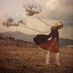 a woman flying a kite on top of a dry grass field