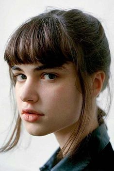 a young woman with bangs is looking at the camera while wearing a black shirt and leather jacket