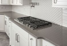 a stove top oven sitting inside of a kitchen next to white cabinets and counter tops