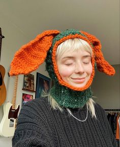 a woman wearing an orange and green knitted bunny hat with ears on her head