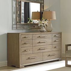 a dresser with a mirror, lamp and vase on it in a living room area