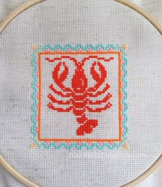 a close up of a cross stitch on a piece of cloth with a wooden hoop