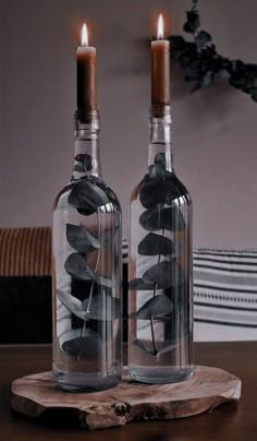 two bottles with candles inside sitting on a table