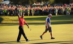 two men walking across a green holding their hands up in the air as people watch