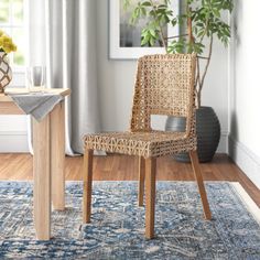 a wicker chair sitting on top of a rug next to a table with a potted plant