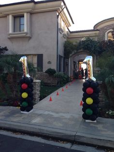 there are two traffic lights made out of balloons in front of a house that is decorated with orange and green cones