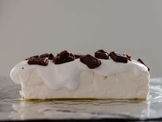 a piece of cake with white frosting and chocolate chips on top, sitting on a glass plate