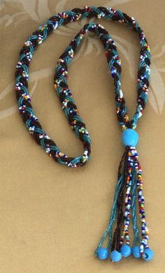 "Featuring this unique blue, brown and multi-colored glass seed bead woven tassel necklace. The necklace measures 28\", not including the tassel. It is in very good vintage condition and does not have a clasp." Hand-strung Multicolor Beaded Lariat Necklace, Adjustable Multicolor Tassel Necklace With Round Beads, Multicolor Round Beads Tassel Necklace For Beach, Multicolor Round Beaded Tassel Necklace For Beach, Adjustable Multicolor Tassel Necklace With 108 Beads, Multicolor Tassel Necklace With Round Beads For Beach, Adjustable Multicolor Tassel Necklace With Colorful Beads, Adjustable Multicolor Beaded Tassel Necklace, Turquoise Beaded Necklace With Tassels And Round Beads