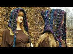 two women wearing crocheted hats in front of a wall