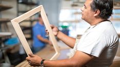 a man holding up a wooden frame in his hands