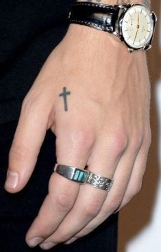 a person with a cross tattoo on their hand and a watch in the other hand