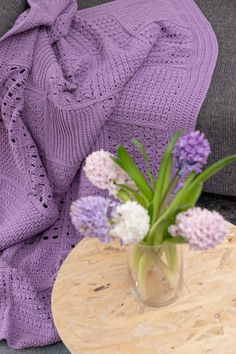 a vase with flowers on a table next to a blanket