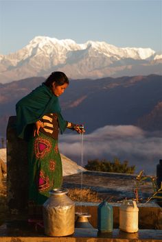 a woman standing on top of a roof next to pots and pans filled with water