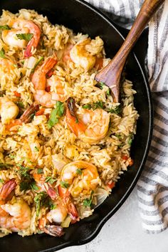 shrimp and rice in a skillet with a wooden spoon on the side, ready to be eaten